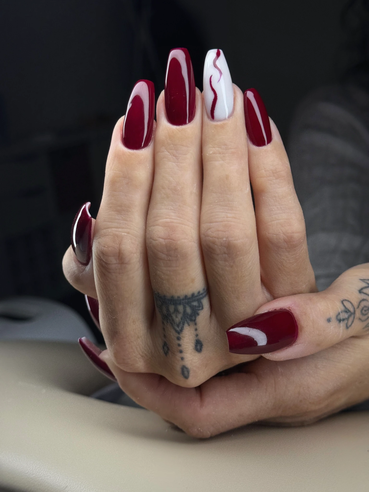Bordeauxrote Gelnägel mit weissem Akzentnagel und geschwungenen Nailart-Linien